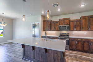 Kitchen with stainless steel appliances, backsplash, light countertops, pendant lighting, and a textured ceiling