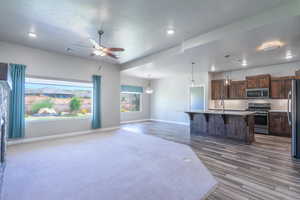 Kitchen with open floor plan, decorative backsplash, a kitchen breakfast bar, appliances with stainless steel finishes, and a textured ceiling