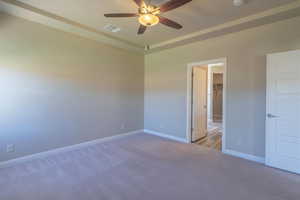 Unfurnished bedroom with carpet floors, a spacious closet, and a ceiling fan