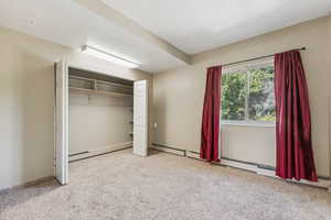 Unfurnished bedroom featuring carpet flooring, a baseboard heating unit, a closet, and a textured ceiling