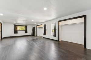Unfurnished living room with dark wood-type flooring, recessed lighting, and a textured ceiling