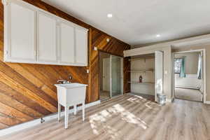 Unfurnished living room featuring wood walls, light wood-style floors, and recessed lighting