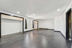 Unfurnished room featuring dark wood finished floors, recessed lighting, a baseboard radiator, and a textured ceiling