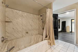 Bathroom featuring tile patterned floors, a combined bath / shower with marble appearance, and a textured ceiling