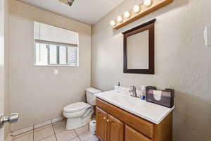 Half bath with a textured wall, tile patterned floors, and vanity