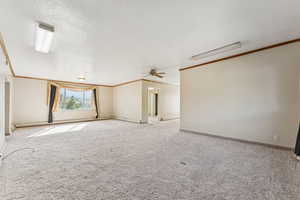 Carpeted empty room with crown molding, a ceiling fan, a textured ceiling, and a baseboard radiator