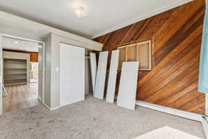 Unfurnished bedroom with wood walls and carpet floors
