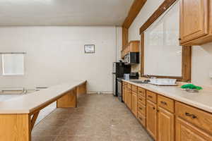 Kitchen featuring appliances with stainless steel finishes, light countertops, a peninsula, and brown cabinetry
