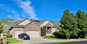 View of front of house featuring a garage, a mountain view, solar panels, concrete driveway, and brick siding