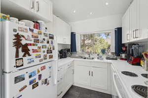 Kitchen with white appliances, light countertops, white cabinetry, and recessed lighting