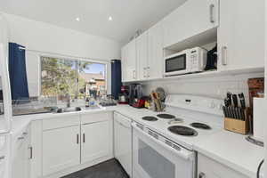 Kitchen featuring white appliances, white cabinetry, tasteful backsplash, light countertops, and recessed lighting