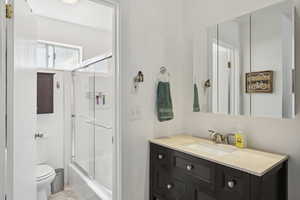 Full bath featuring vanity and bath / shower combo with glass door