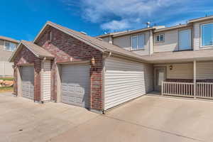 Traditional-style home with brick siding, driveway, an attached garage, and a shingled roof