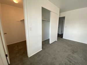 Unfurnished bedroom with dark carpet and a closet