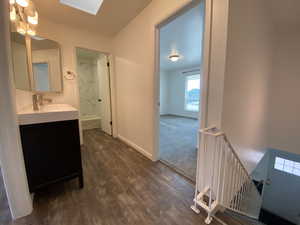 Full bath featuring vanity, wood finished floors, a skylight, and bathing tub / shower combination