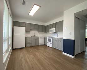 Kitchen featuring gray cabinetry, white appliances, and light wood-type flooring