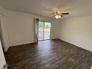 Empty room featuring dark wood-style flooring, a textured ceiling, and a ceiling fan