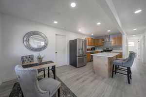 Kitchen with appliances with stainless steel finishes, light countertops, light wood finished floors, a kitchen island, and a breakfast bar