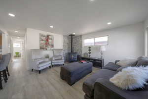 Living area with a wood stove, plenty of natural light, light wood finished floors, and recessed lighting