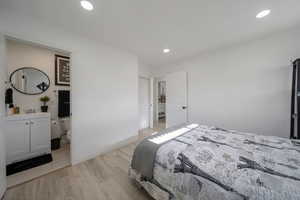 Bedroom with light wood finished floors, recessed lighting, and ensuite bathroom