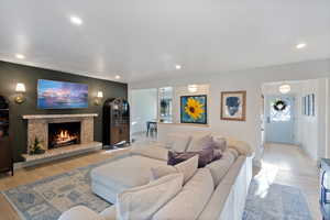 Living room featuring light wood-type flooring, recessed lighting, and a lit fireplace