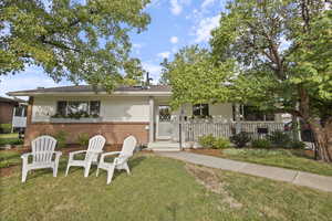 View of front of home featuring brick siding, a front lawn, and covered porch