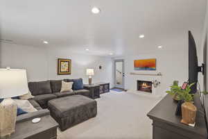 Carpeted living room featuring a lit fireplace and recessed lighting