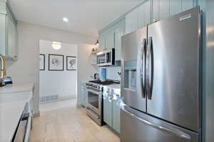 Kitchen with appliances with stainless steel finishes, light wood finished floors, recessed lighting, and backsplash