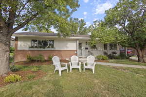 Ranch-style home with brick siding, a front lawn, covered porch, and a shingled roof