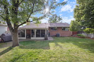 Back of property featuring a sunroom, roof with shingles, and brick siding