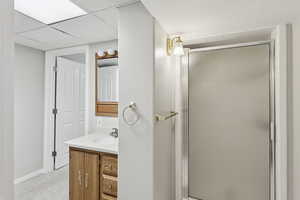 Full bathroom with vanity, a shower stall, and a paneled ceiling