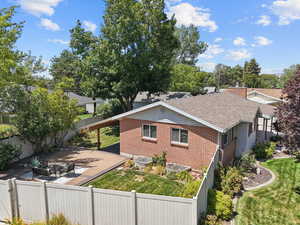 View of property exterior featuring roof with shingles, brick siding, a patio area, and a carport