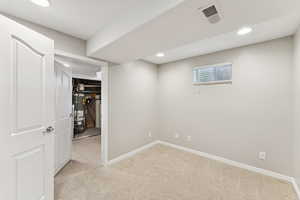 Unfurnished bedroom featuring light colored carpet, recessed lighting, strapped water heater, a walk in closet, and light tile patterned flooring
