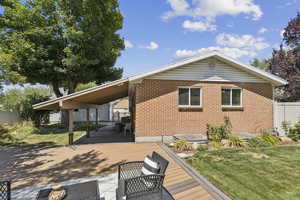 Rear view of property featuring a wooden deck and brick siding
