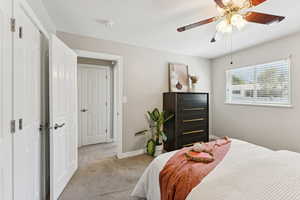 Bedroom with light carpet, ceiling fan, and a closet