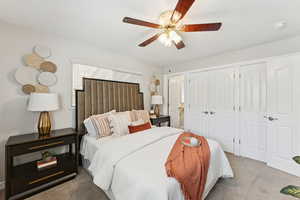 Carpeted bedroom featuring multiple closets and a ceiling fan