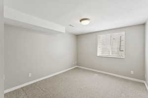 Carpeted spare room featuring baseboards