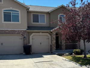 Traditional-style home with an attached garage, driveway, stucco, brick, stone siding and a shingled roof