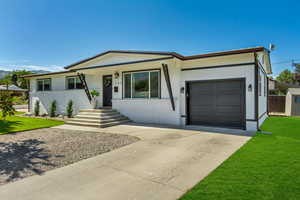 Single story home with brick siding, an attached garage, driveway, and a front lawn