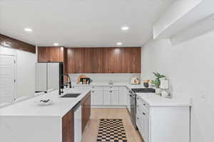 Kitchen with stainless steel gas range, light wood finished floors, light countertops, recessed lighting, and a kitchen island with sink