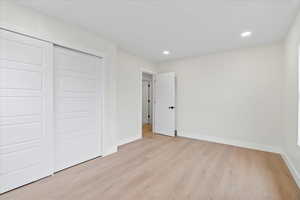 Unfurnished bedroom with light wood-style flooring, recessed lighting, and a closet