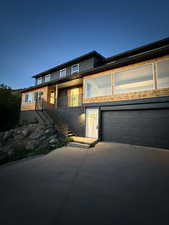 Modern home featuring stairs, brick siding, and concrete driveway