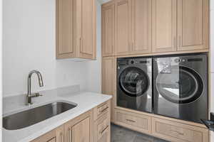 Washroom with separate washer and dryer, cabinet space, and dark tile patterned flooring