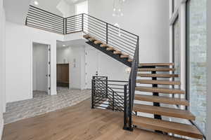Stairway featuring a high ceiling, wood finished floors, and recessed lighting