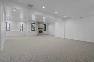 Unfurnished living room with light colored carpet, a large fireplace, recessed lighting, and beam ceiling