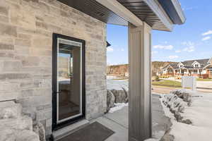 Doorway to property featuring stone siding and a residential view