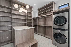 Laundry room featuring estacked washer and dryer and a chandelier