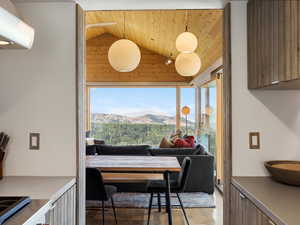 Dining room featuring lofted ceiling, wooden ceiling, a mountain view, and light wood finished floors