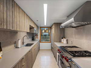 Kitchen featuring island range hood, stainless steel appliances, decorative backsplash, and light countertops