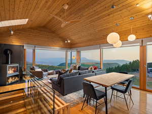Dining area featuring a mountain view, a wood stove, wood ceiling, wood-type flooring, and vaulted ceiling